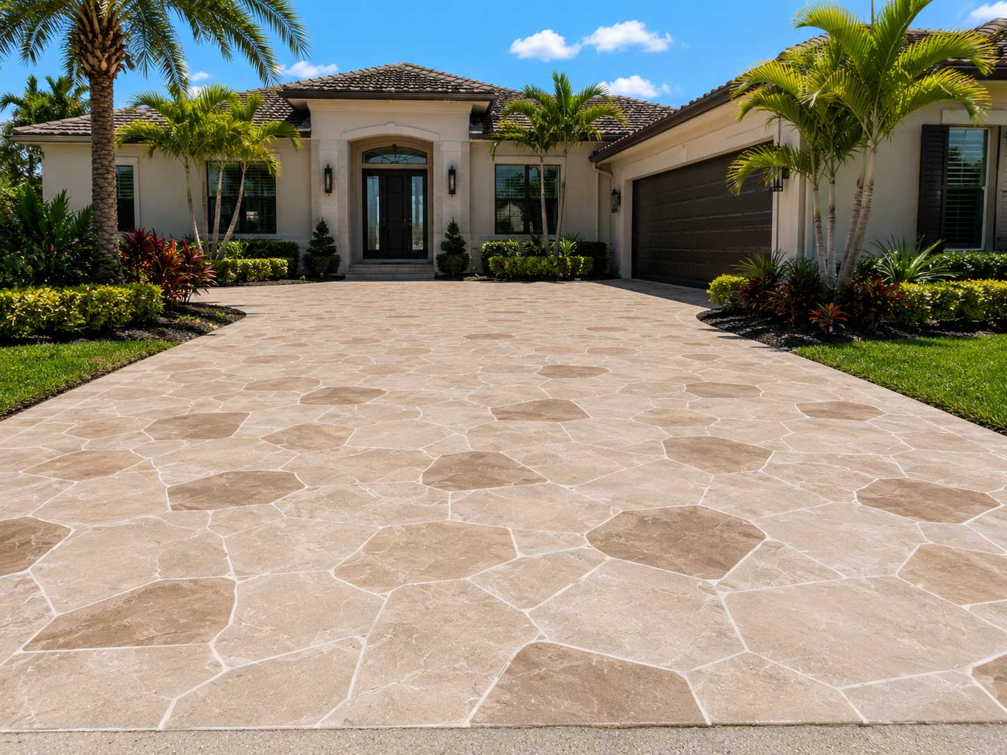 Decorative stamped concrete driveway with a natural stone pattern and tropical landscaping