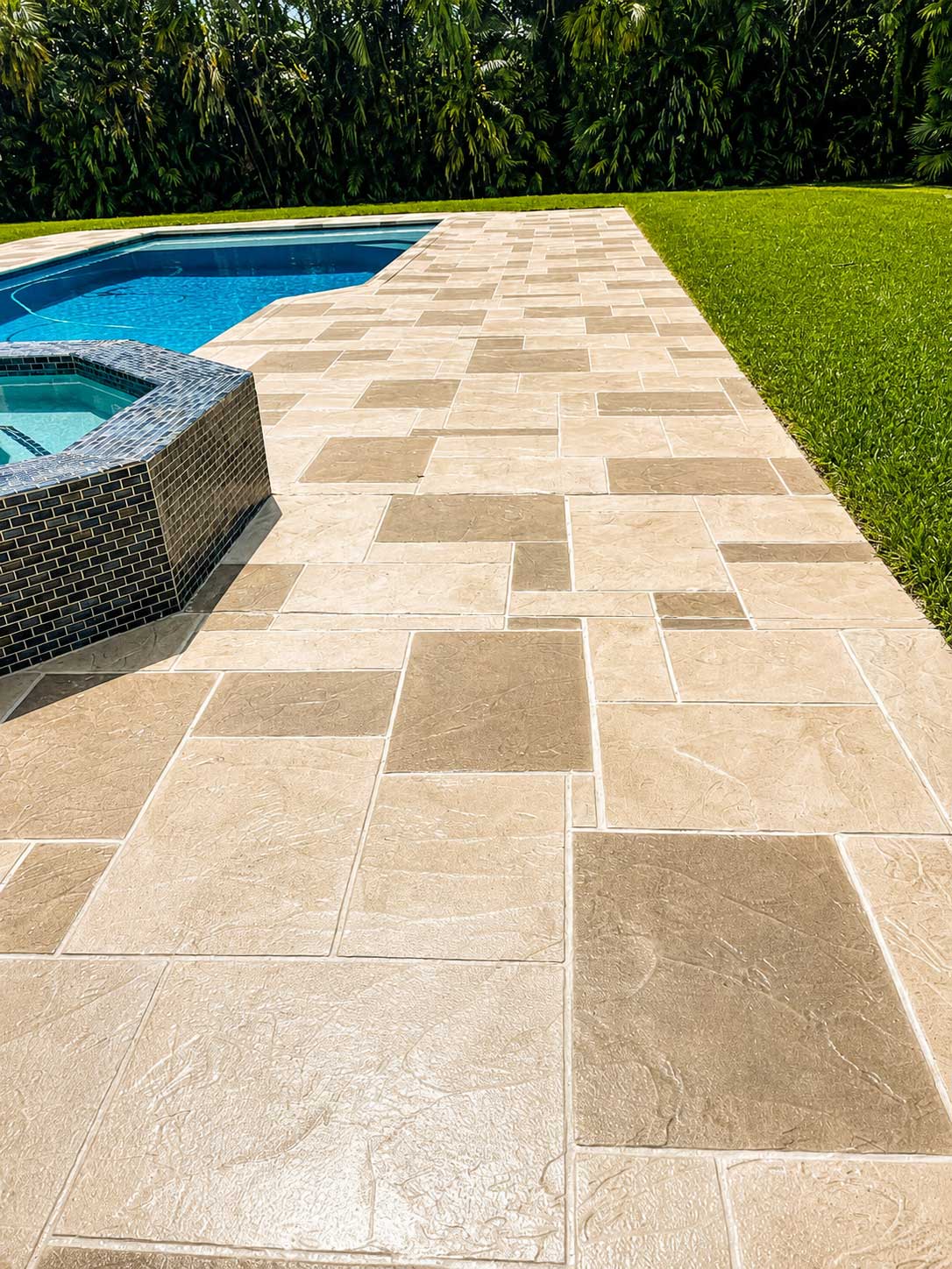 Tan rectangular paver pool deck with a raised spa in Palm Beach and Broward County