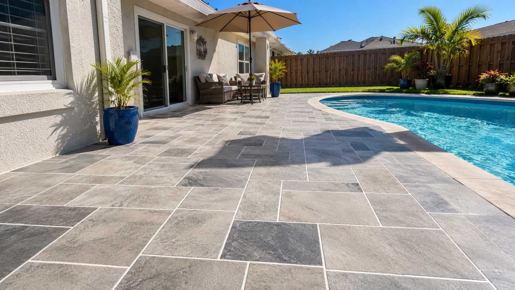 Concrete overlay patio with a gray stamped slate finish beside a free-form pool in Palm Beach and Broward County