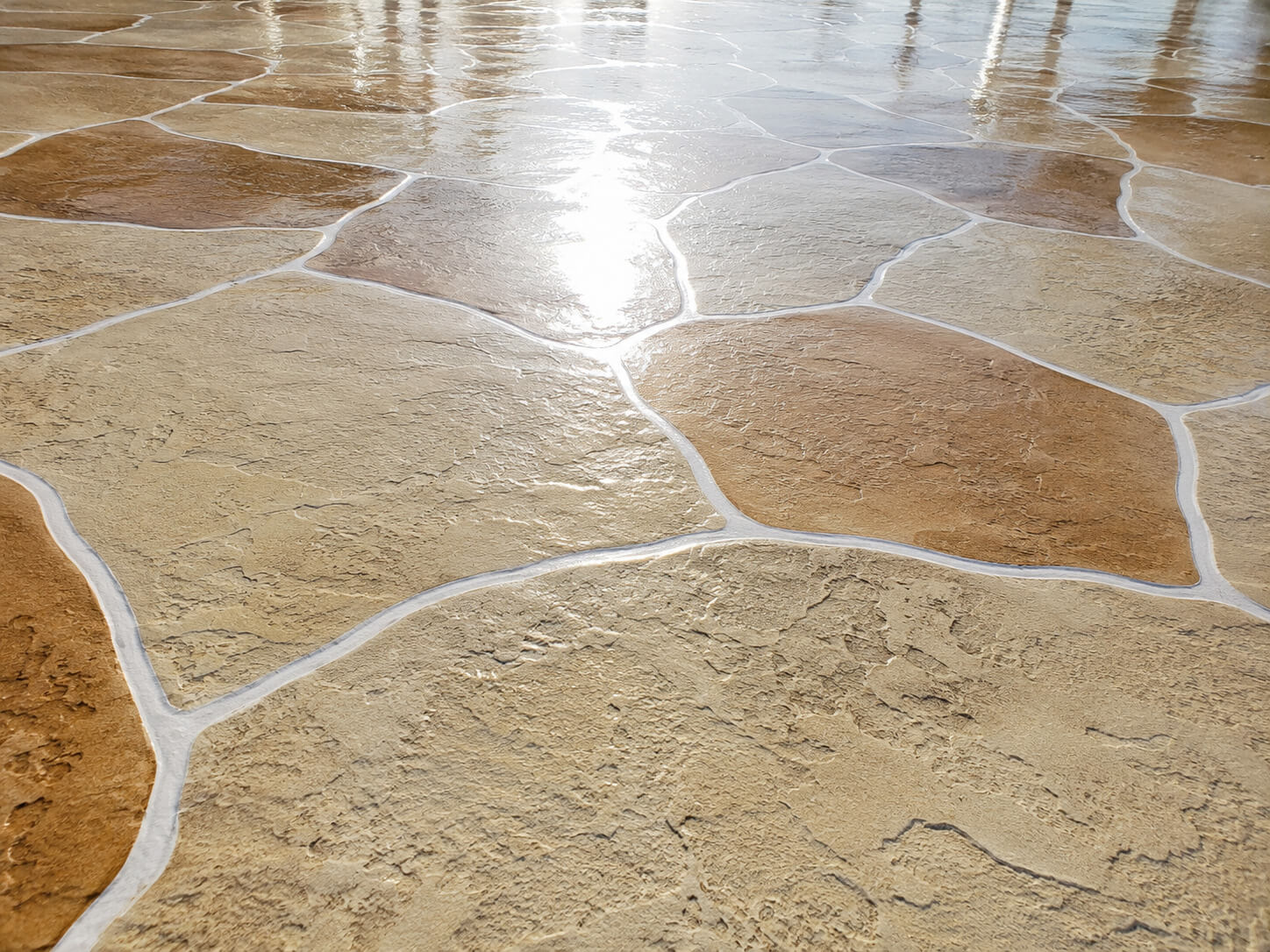 Tan colored stamped concrete overlay pool deck with a sealed flagstone finish