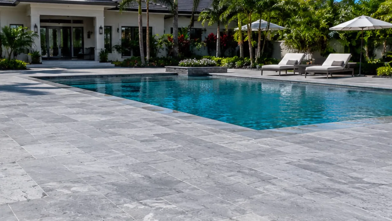 Renovated pool deck with travertine pavers around a swimming pool