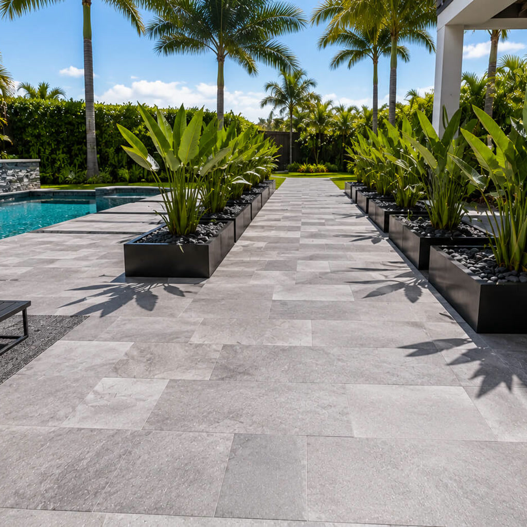 Gray paver walkway running between black planters to connect the pool deck with the rest of the backyard in Jupiter
