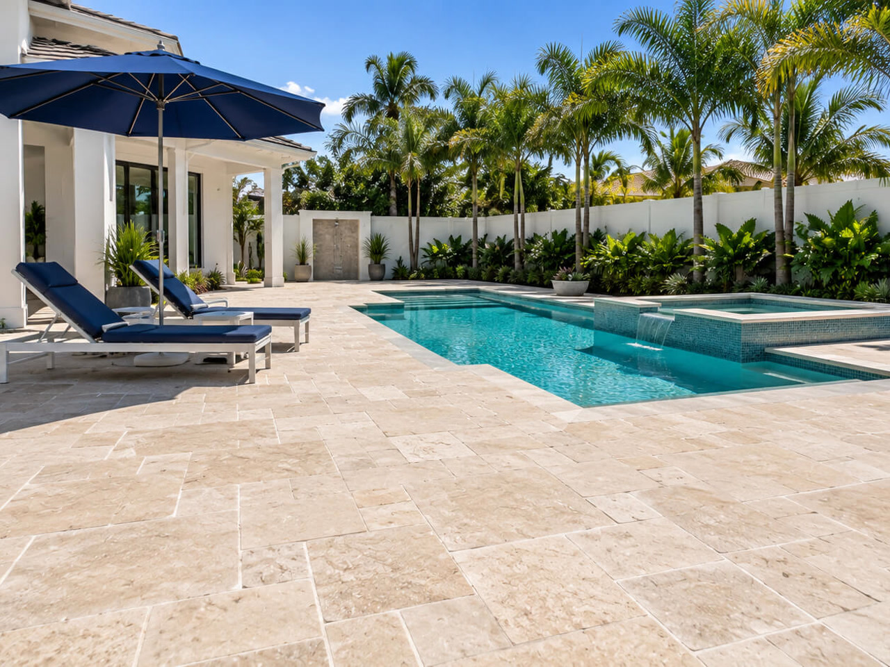 Travertine paver pool deck installed in a French pattern for a Pompano Beach homeowner, beside a pool with a raised spa and sheer descent