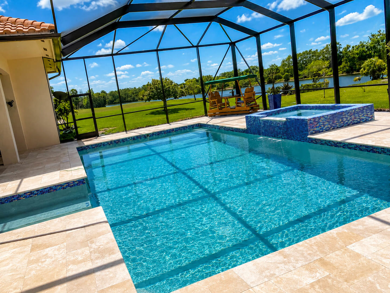 Renovated pool and raised spa with mosaic tile under a screen enclosure at a Jupiter property