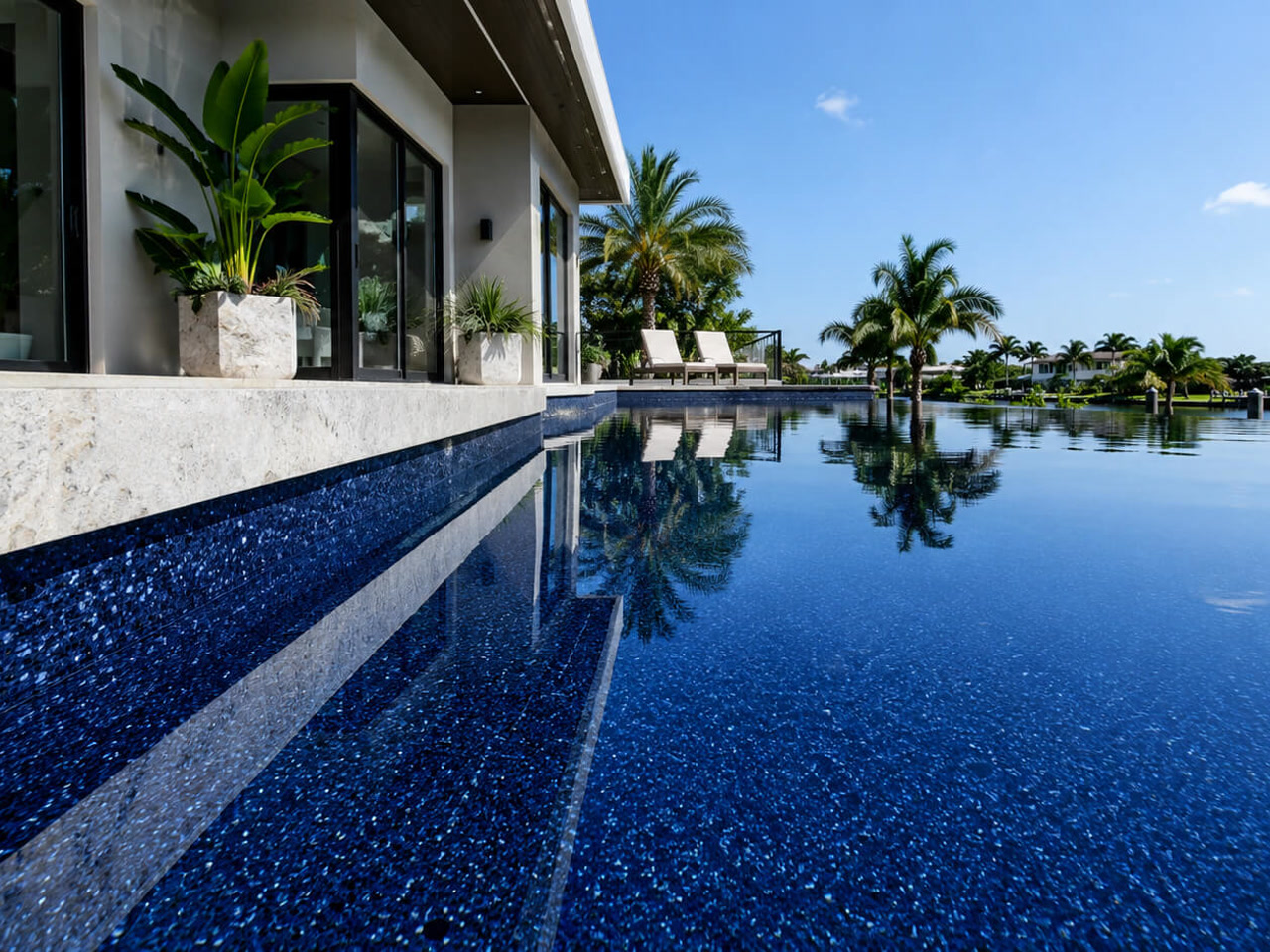 Finished pool resurfacing in a dark pebble finish, with sheer descents spilling over gray marble coping in a Boynton Beach neighborhood