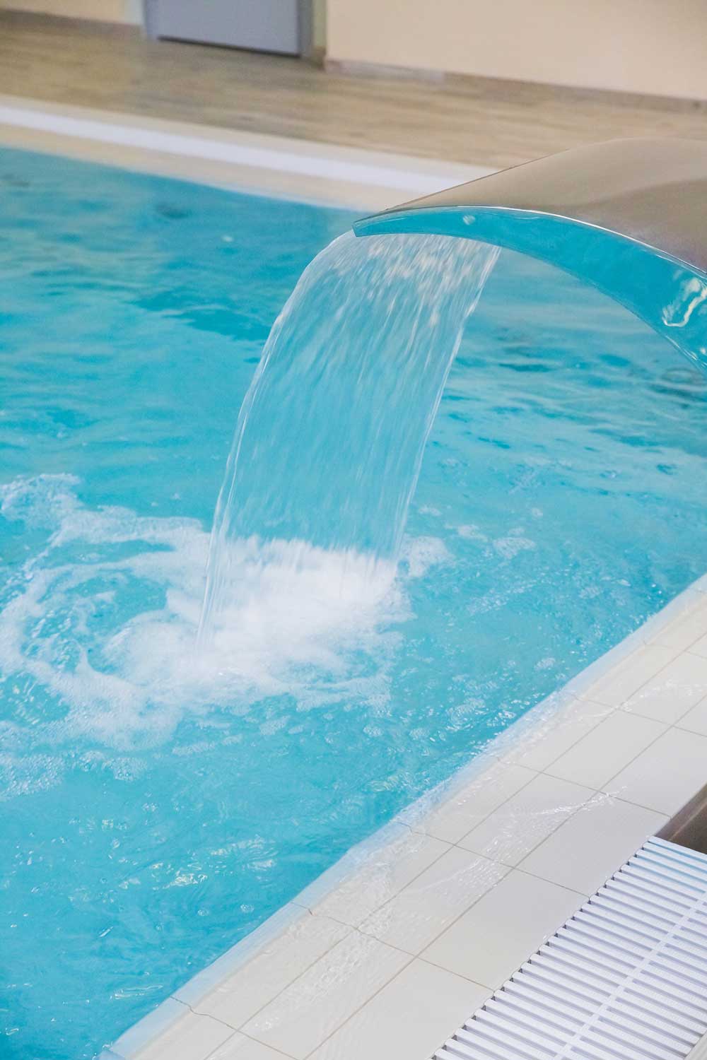 Curved stainless steel waterfall pouring into a swimming pool in Juno Beach