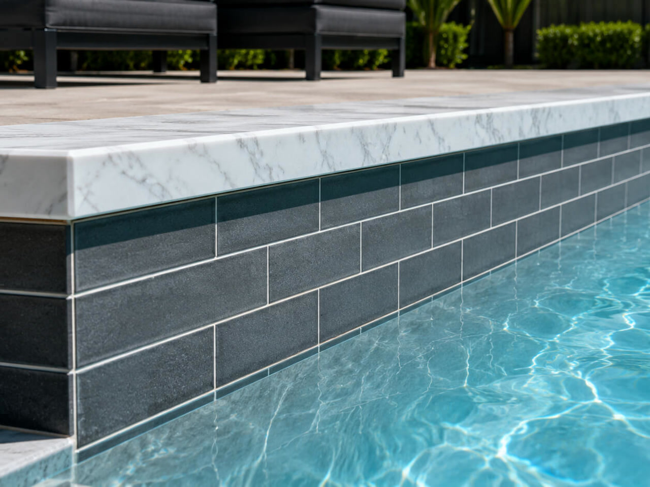 White marble coping cap over charcoal subway tile on a Palm Beach Gardens pool wall