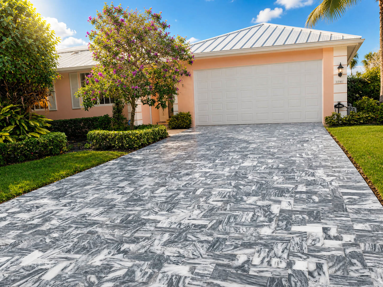 Gray veined marble paver driveway laid in herringbone leading to the garage of a coral Florida home