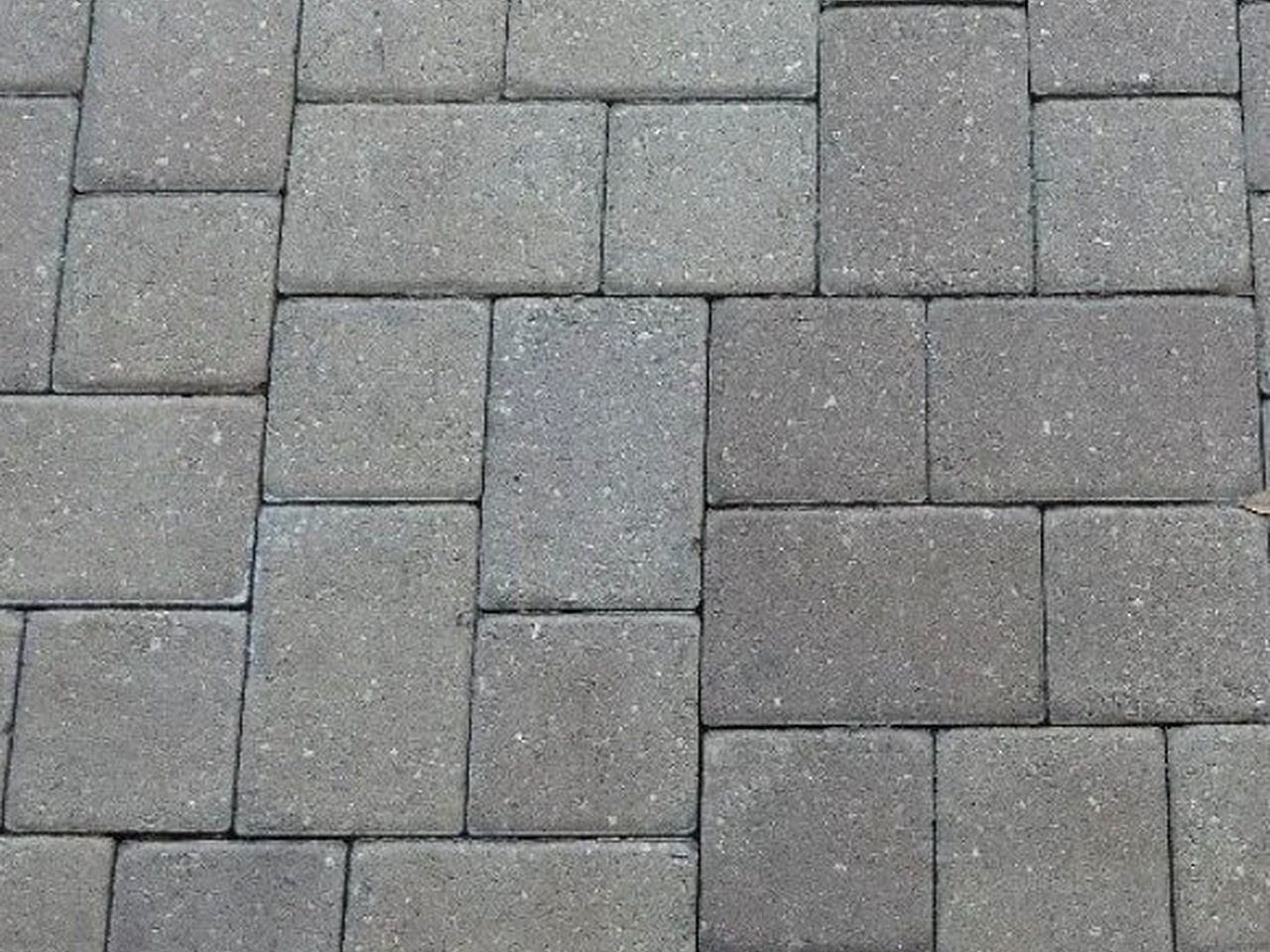 Close up of gray concrete pavers set in a modular random pattern with tight sand joints