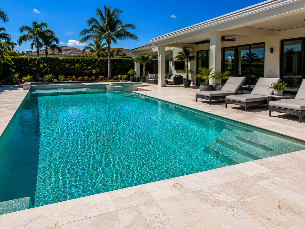 Resurfaced rectangular pool with an integrated spa and travertine deck behind a Florida home