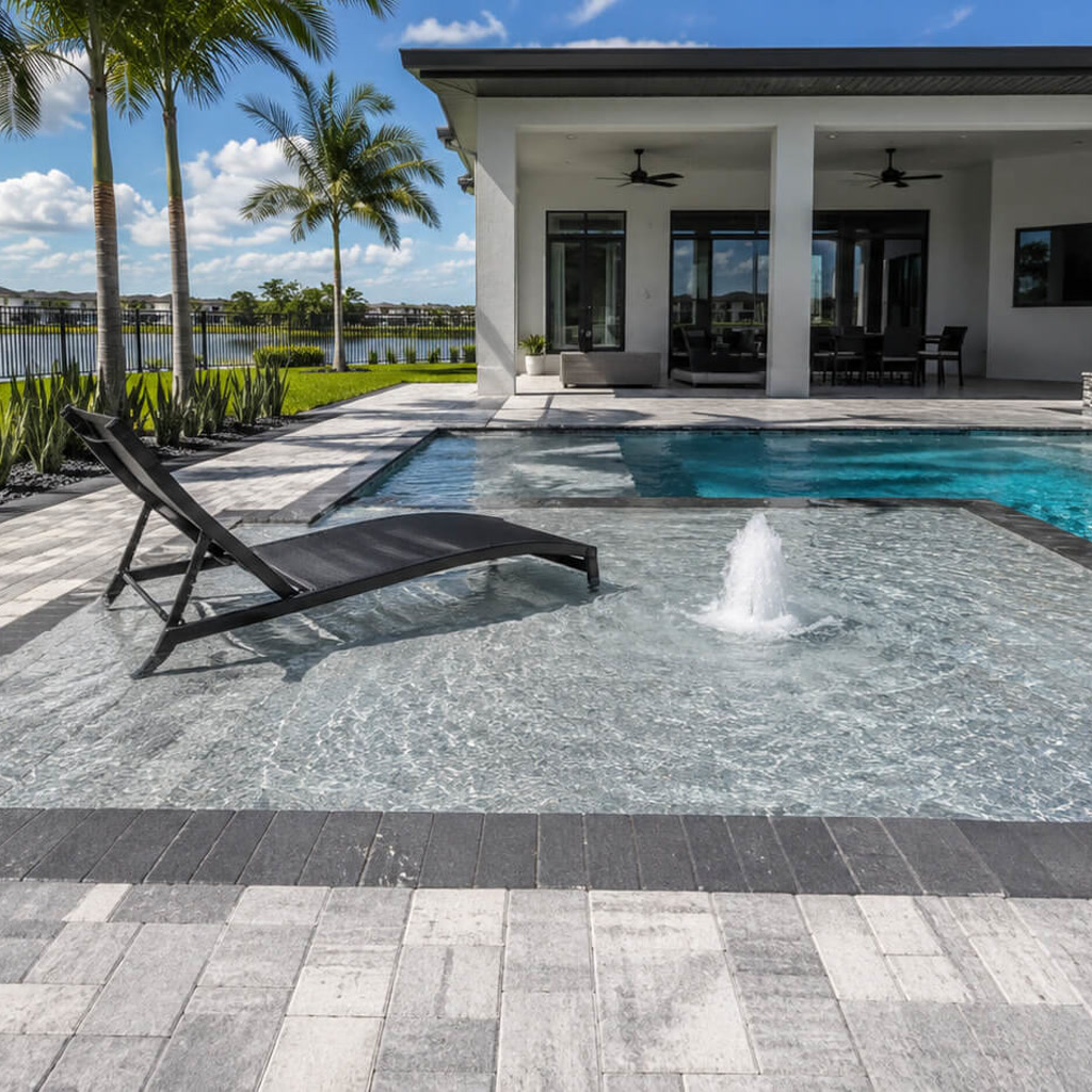 Sun shelf with a bubbler and in water lounger connecting the pool to a covered lanai on a lakefront lot
